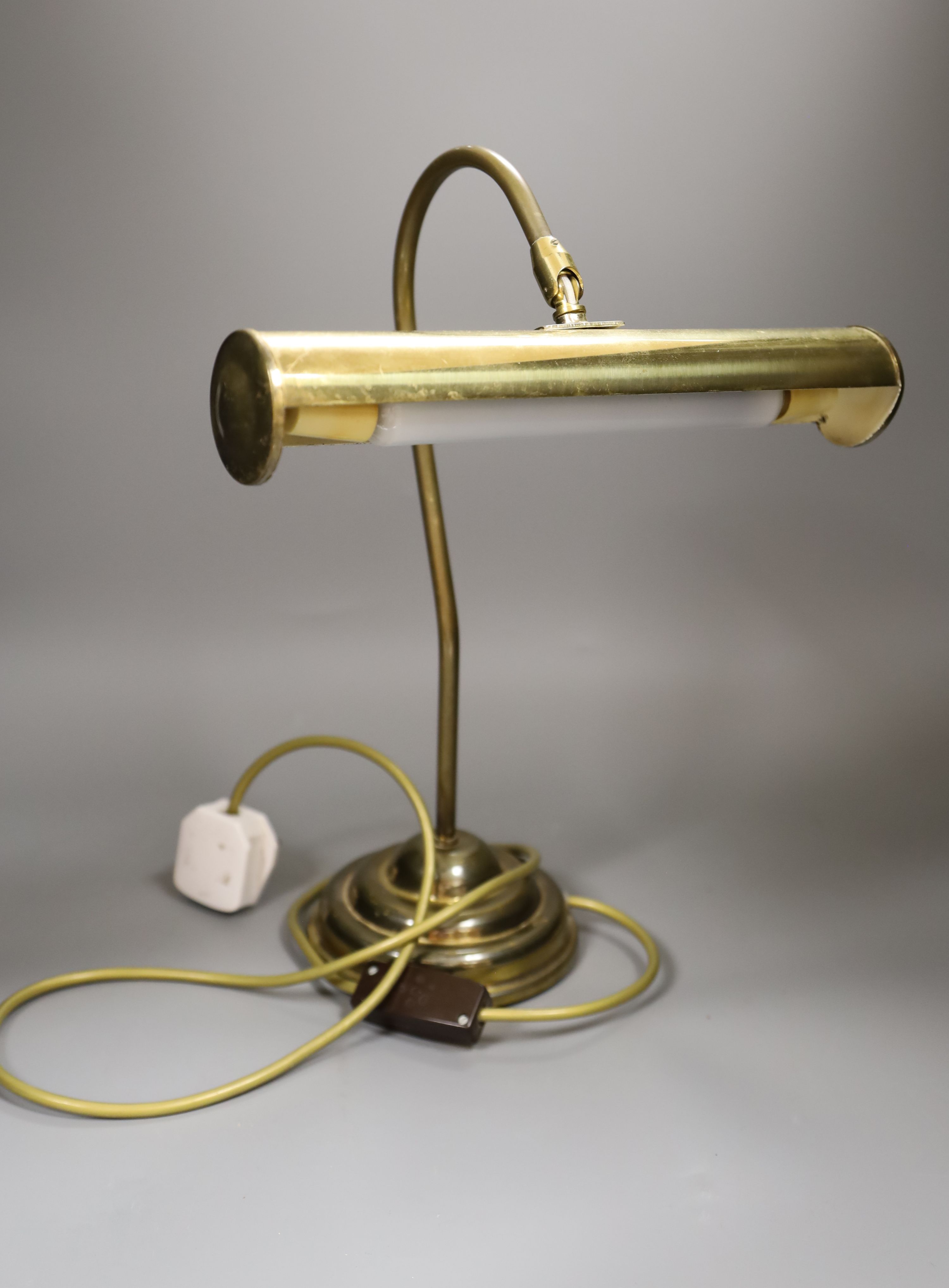A copper overlaid fender, length 69cm, and a brass desk lamp
